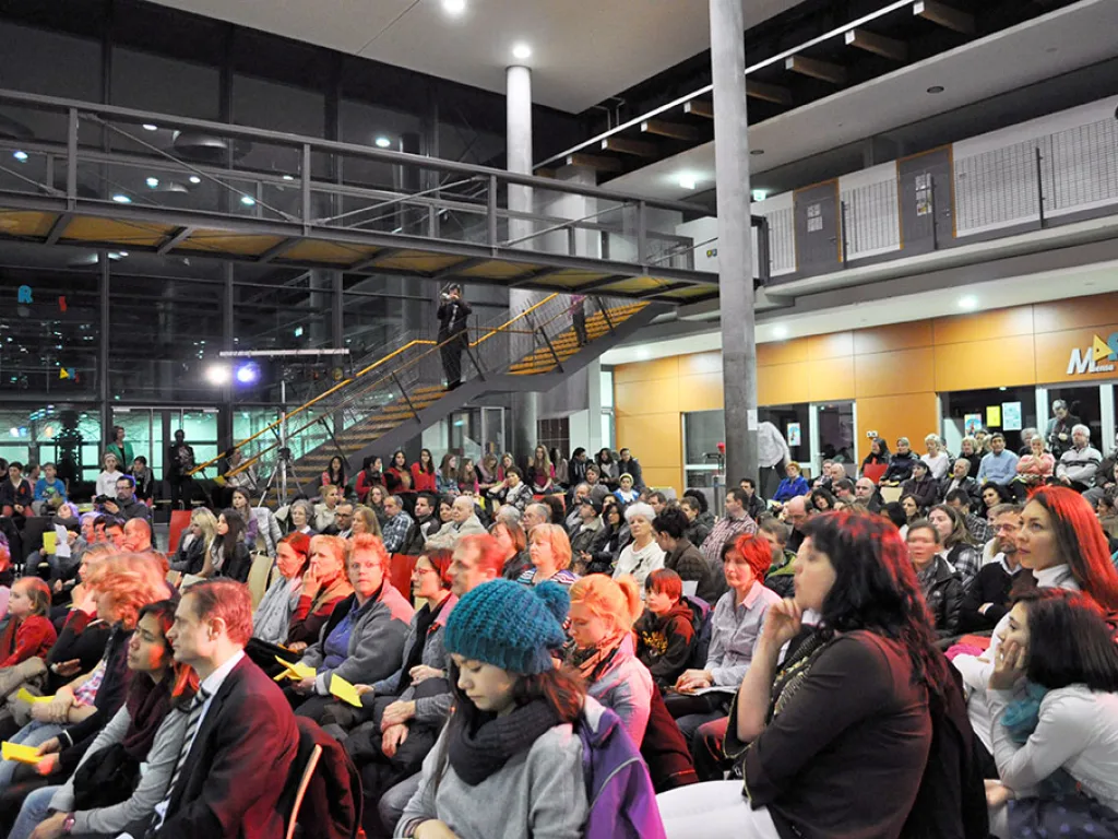 Volles Foyer mit sitzendem Publikum.
